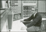 Researcher surrounded by control panels, 1973