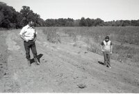 Two men stand in dusty road