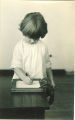 Little girl standing and writing at a table, The University of Iowa, 1920s
