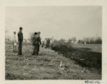 Individuals observing a tractor building terraces, 1949