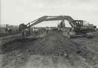 Several people standing by two Komatsu Excavators with a smaller farm machine in background