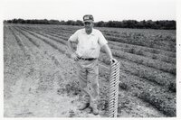 Man stands next to pipe in field