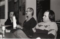 Three men sit at table at meeting