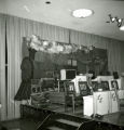 A man preparing the stage for the Les Elgart band with a backdrop of a train for the Homecoming Dance, 1965