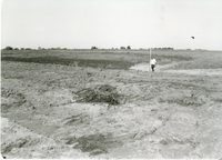 Man Stands by TOT Pipe in Field