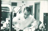 Dental student looking at a small girl's teeth, The University of Iowa, 1940s