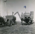 Farmer unloading crops from combine to wagon, 1955