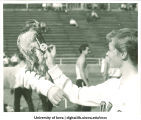 Cheerleader placing pin on hawk during Homecoming festivities, The University of Iowa, November 3, 1956