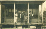 Men, woman and girl posing on porch of store, Morley, Iowa, 1910s