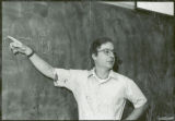 Professor Peter Reilly stands before a blackboard, 1975