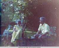 Elizabeth, Bill and corgy sit on patio outside sun porch 