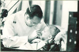 Dental student looking at a small girl's teeth, The University of Iowa, 1940s