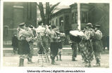 Marching band in clown costumes in Mecca Day parade, The University of Iowa, 1920