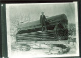 Man standing on wagon holding boiler equipment outside, The University of Iowa, 1890s