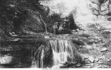 Man standing at top of waterfall in Devil's Den, Iowa, late 1890's or early 1900s