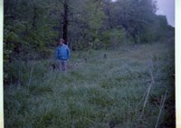 Man in Blue Jacket Walks Beside Woods