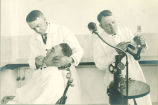 Dentist examining patient while another works with model of teeth, The University of Iowa, 1930s?