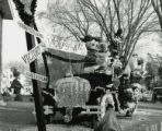 Homecoming law display of Disney characters and Cy riding in a jalopy in Victoryland, 1961
