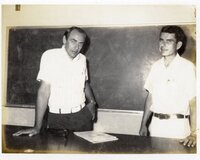 1970s Two unidentified men stand in front of chalkboard