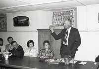 Standing man speaks to group at meeting