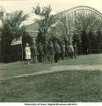 Group of officers standing near a flag at attention near Armory, The University of Iowa, 1950s