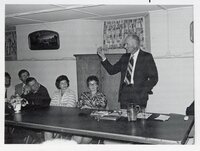 Standing man speaks to group at meeting
