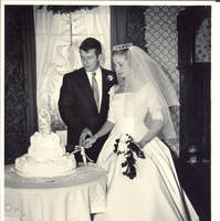 Frindy and John, Sr., look at cake while cutting it, in dining room 