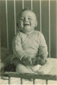 Smiling baby sitting in a crib, The University of Iowa, 1920s