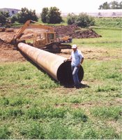 Unidentified man standing next to large pipe