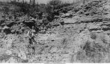 Man in front of section of Maquoketa shales, Graf, Iowa, late 1890s or early 1900s
