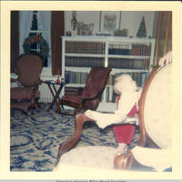 John, Jr. standing in the parlor by chair