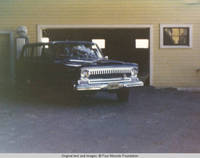 Truck parked in front of barn and gas pump
