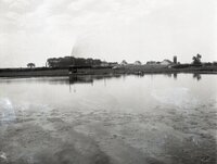 Large pond  with farm buildings on the other side