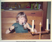 John, Jr. sitting at table drinking from glass