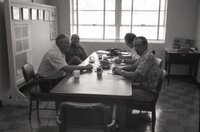 Four men sit at a table at an office meeting