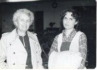 Two unidentified women pose for photo in a room with folding chairs
