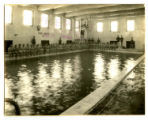 Men sitting around the swimming pool in State Gymnasium