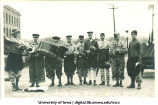 Marching band in clown costumes in Mecca Day parade, The University of Iowa, 1920