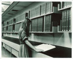 Woman reading National Union Catalog volume in Main Library, the University of Iowa, 1970s
