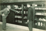Men looking at a cabinet of chemistry compounds, The University of Iowa, 1930s