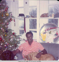 Ainsley Benard sitting on couch at Christmas with Victoria in his lap and Sadie at his side