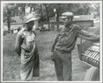 Two men talking by a piece of farm equipment