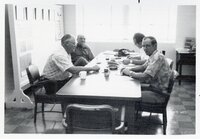 Four men sit at a table at an office meeting