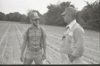 Man with hat, sunglasses, and beard in grassy field