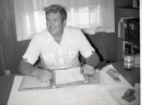 Unidentified Man Sits at Desk with Notebook
