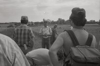 Man with hat, sunglasses, and beard in grassy field