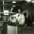 Pharmacy student adding to vat in pharmacy laboratory, The University of Iowa, 1930s