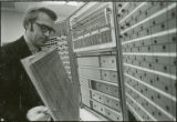 Professor checking front panel of equipment, 1970