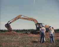 Four People Watching Komatsu Excavator in Field