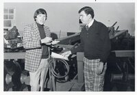 Two men stand by Ford service sign